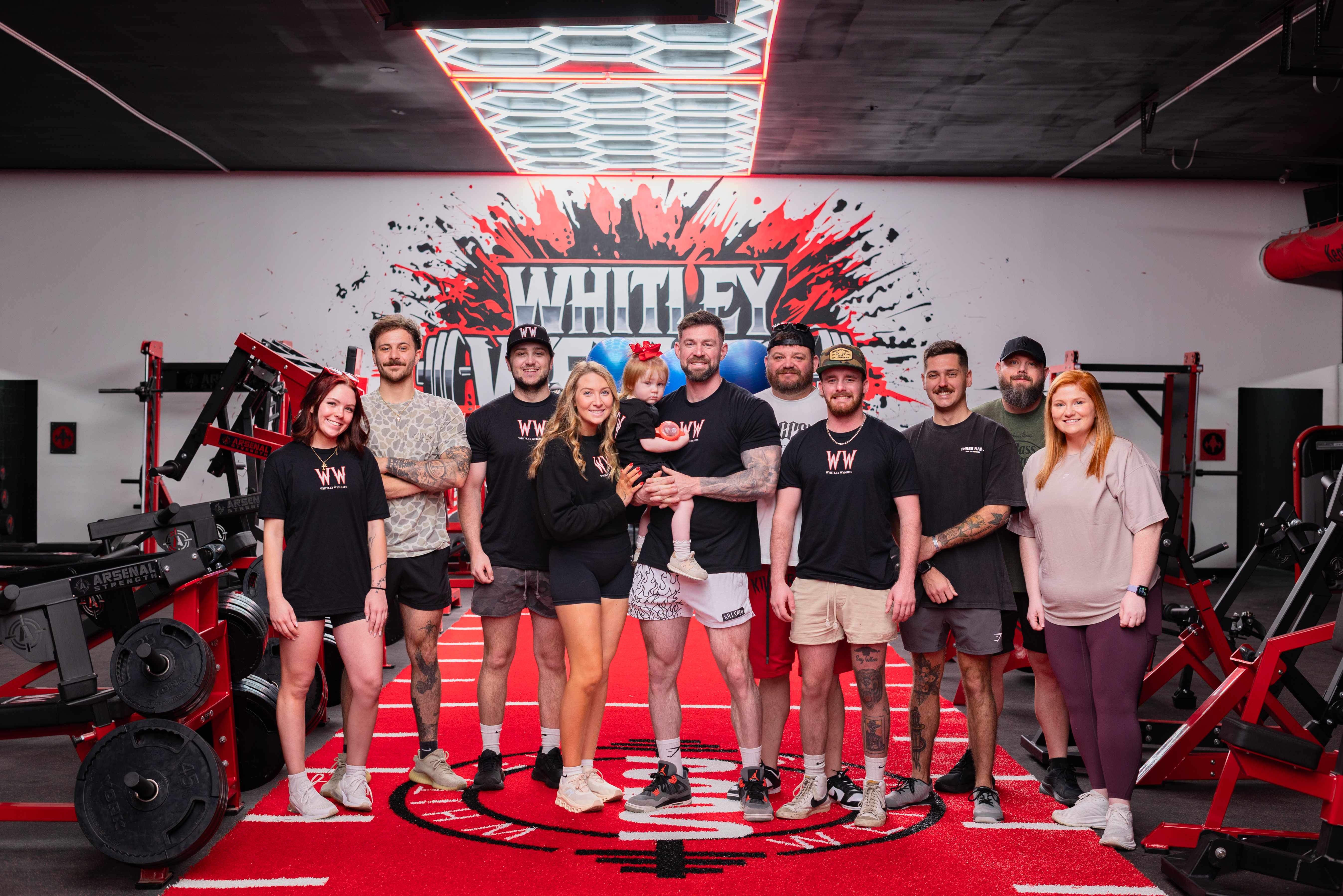 The Whitley Weights team on the red turf in front of the mural
