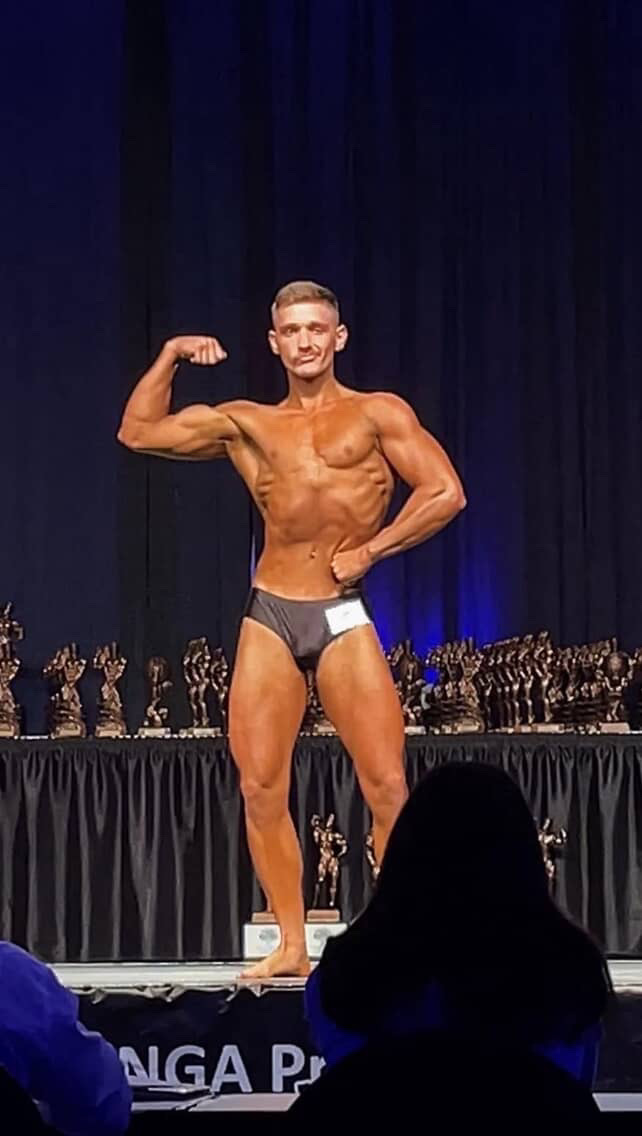Men's physique competitor posing on the NGA Pro stage